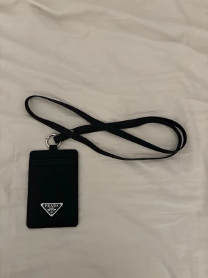 Svart plånbok med axelrem - Jag säljer en helt ny svart plånbok med axelrem. Perfekt för dem som har svårt att hålla koll på sitt bank kort eller id-kort. 