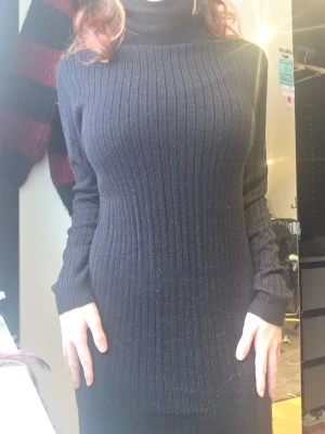 Svart ribbad stickad klänning JDY - Svart långärmad stickad klänning från Jacqueline de Yong i storlek M. Klänningen har polokrage, ribbat mönster och är figurnära med en klassisk och enkel look. Perfekt för dig som gillar stilrena och bekväma outfits.