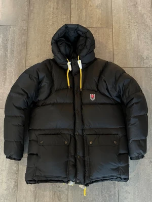 Fjällräven Expedition Down Jacket - Fjällräven Expedition Down Jacket i färgen svart.  Den tjockare modellen. Storlek XXS, men väldigt stor i storleken och sitter som en S/M.                                                                               Jackan är i nyskick, helt utan konstigheter, och endast använd ett fåtal gånger av tidigare säljare. Av mig bara prövad.