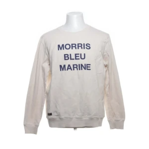 Morris tröja  - Cremefärgad sweatshirt från Morris med mörkblå text 'MORRIS BLEU MARINE' på bröstet. Tröjan har rund hals, långa ärmar och ribbade muddar vid ärmslut och nederkant. Tillverkad i mjuk bomull, perfekt för chill dagar. Snygg och enkel design som funkar året runt. Storlek L men utgå från måtten.NOPPRIG men annars i bra skick. S2