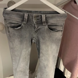 Pepe Powerflex grå jeans straight leg - Snygga grå jeans från pepe med straight leg och low waist. Modellen är Powerflex med regular fit, har två knappar i midjan och klassiska fem fickor. Cool tvättad look och detaljerade bakfickor med vågig söm.