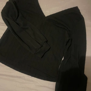 Svart v-ringad långärmad tröja - Säljer en svart långärmad tröja med v-ringning. Tröjan har en lätt struktur i tyget och är enkel men stilren, perfekt att matcha med jeans eller kjol. Passformen är normal och materialet känns mjukt mot huden.