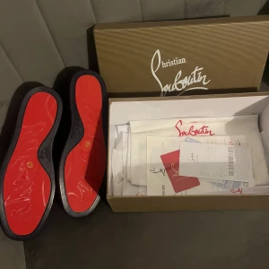 Loubs - Säljer ett par mörkblå sneakers från Christian Louboutin i lyxig mocka med klassisk röd sula. Skorna har rund tå, snörning och diskret branding. Perfekta för dig som vill sticka ut med exklusiv stil och detaljer. Kommer med originalkartong och tillbehör.