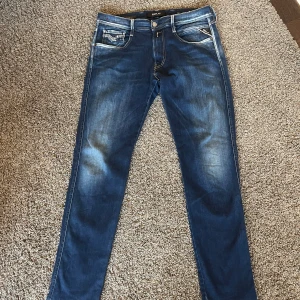 Replay Hyperflex skinny jeans blå - Snygga Replay Hyperflex jeans i mörkblå tvätt med slitningar och kontrastsömmar. Modellen är skinny fit med klassiska fem fickor och stretchigt jeanstyg för extra komfort. Perfekta för dig som gillar en smal siluett och vill ha jeans som sitter tajt hela vägen.