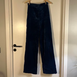 Mörkblå manchesterbyxor med hög midja - Säljer ett par mörkblå manchesterbyxor med hög midja och breda ben. Byxorna har en klassisk rak siluett och är tillverkade i mjuk manchester som ger en cool vintagekänsla. Perfekta för dig som gillar retrostil och vill sticka ut med en unik look.