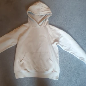 Beige hoodie med huva och ficka - Säljer en stilren beige hoodie med huva och stor magficka. Tröjan har långa ärmar och en klassisk passform, perfekt för en avslappnad look. Tillverkad i mjukt bomullsmaterial som känns skönt mot huden.