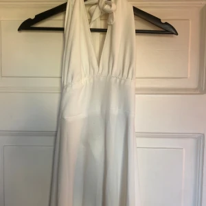 Vit långklänning  - Vit långklänning i storlek S. Är i jättefint skick men har tecken på användning såsom någon enstaka läs tråd och två mindre ljusa fläckar på baksidan. Varan är köpt second hand på Sellpy för 400 kr, aldrig använd av mig men säljer vidare för 250.