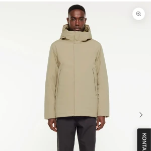 Beige vinterdunjacka med huva - Stilren beige dunjacka från Elvine med huva och dragkedja. Jackan har en clean look, två sidofickor med dragkedja och quiltad insida. Nypris 3499kr, Storlek M. Lappen avtagen men aldrig använd