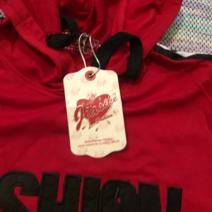 Röd hoodie med tryck från Jiasike och tillhörande byxor  - Röd hoodie från Jiasike med svart tryck 'FASHION' på bröstet. Tröjan har korta ärmar, huva med svarta snören och är tillverkad i ett mjukt material. Perfekt för en sportig look eller chill dagar. I komplext så finns även långa mjuka byxor. Passar storlek M. Kläderna är enbart provade och säljer på grund av fel storkek , alltså det är för små för mig