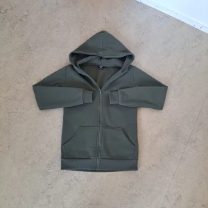 Grön - hoodie🍏 - Mörkgrön hoodie från New Yorker med hel dragkedja, huva och två stora fickor framtill. Tröjan är i mjuk bomullsblandning och har ribbade muddar vid ärmslut och nederkant. Perfekt för kyliga dagar och enkel att matcha med jeans eller joggers.