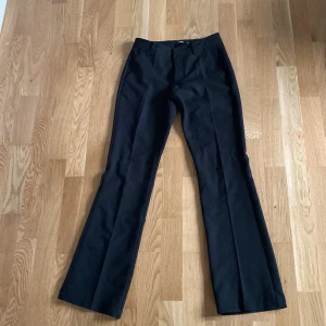 Svarta bootcut kostymbyxor BikBok - Svarta kostymbyxor från BikBok i storlek 34. Byxorna har bootcut-modell med pressveck, hällor för bälte och två fuskfickor bak. Snygg passform och klassisk look, perfekta till en trendig outfit.Dom är låg midjade 