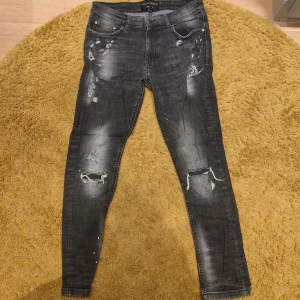 Supply and demand jeans - Säljer ett par svarta slim jeans med coola slitningar och trasiga detaljer på benen. Jeansen har fem fickor, låg midja och är i stretchigt material för en skön passform. 