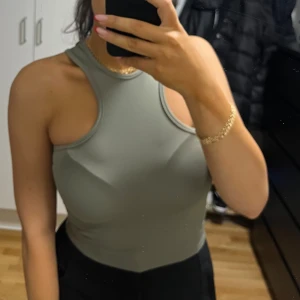 Grå ärmlös linnetopp - Säljer en stilren grå linnetopp med hög hals och ärmlös design. Toppen har en tight passform och är tillverkad i mjukt, stretchigt material som sitter snyggt mot kroppen. Perfekt för dig som gillar minimalistisk och clean stil.