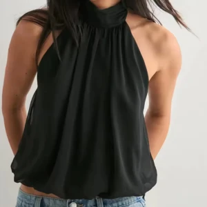 Svart halterneck topp - Halterneck topp från Nelly storlek s, helt ny endast testad. Säljer en svart halterneck topp med hög krage och öppen rygg. Toppen är ärmlös och har en lös, flowy passform som ger en chill vibe. Materialet är lätt och känns skönt mot huden, perfekt för varma dagar eller när du vill sticka ut lite extra.