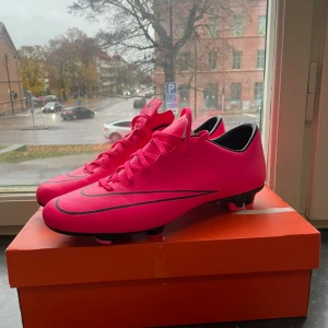 Nike mercurial Vapor XFG Hyperpink-black - Säljer ett par grymt snygga Nike Mercurial fotbollsskor i en riktigt iögonfallande rosa färg med svarta detaljer och logga. Skorna har snörning och platt sula med dobbar för bästa grepp på planen. Perfekta för dig som vill sticka ut på matchen!