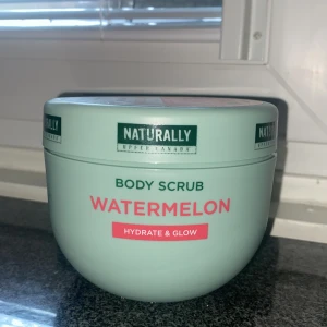 Naturally Watermelon Body Scrub - Fräsch body scrub med vattenmelon-doft från Naturally Upper Canada. Kommer i en mintgrön rund burk med rosa och gröna detaljer. Perfekt för att återfukta och ge glow till huden. Hydrate & Glow-formula för en mjuk känsla.