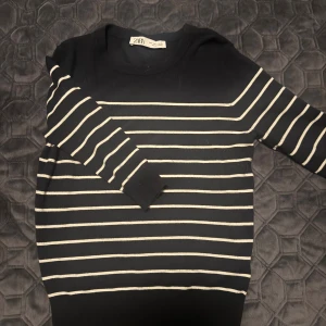 Svartvit randig tröja från Zara - Svart långärmad tröja från Zara med vita horisontella ränder. Tröjan har rund hals och är tillverkad i mjukt material som sitter skönt mot kroppen. Perfekt för dig som gillar klassisk stil med en modern touch.