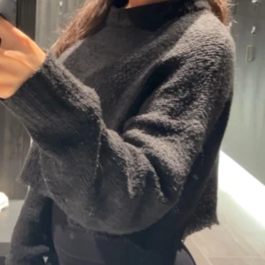 Svart croppad stickad tröja - Svart croppad stickad tröja med lång ärm och breda muddar. Tröjan har en avslappnad passform och är perfekt för lager-på-lager. Enkel och stilren design som funkar till många outfits.