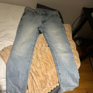 Ljusblå straight jeans från H&M - Säljer ett par ljusblå jeans från H&M med straight regular fit. Klassisk femficksmodell med normal passform och raka ben. Jeansen har en snygg tvättad look och är tillverkade i bomull. Perfekta för en avslappnad och stilren vibe.