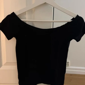 Svart offshoulder topp Gina Tricot XS - Säljer en svart offshoulder topp från Gina Tricot i storlek XS. Toppen har korta ärmar och en tight passform som sitter snyggt över axlarna. Perfekt att styla med jeans eller kjol för en trendig look.