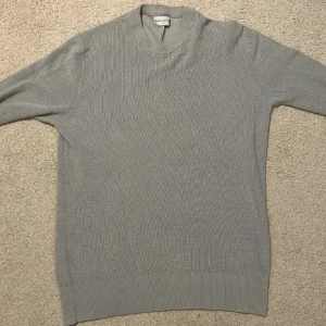 Grå stickad tröja These Glory Days - Snygg grå stickad tröja från These Glory Days i storlek small. Tröjan har rund halsringning, ribbade muddar och är långärmad. Perfekt för lager-på-lager och enkel att matcha med jeans eller chinos.