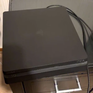 PlayStation 4 Slim - Sony PlayStation 4 Slim i gott skick, säljes med tre original DualShock 4-kontroller. Konsolen har mindre ytliga märken men fungerar utmärkt. Perfekt för spelkvällar med vänner eller familj.