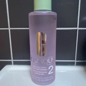 Clinique Clarifying Lotion 2 400ml - Clinique Clarifying Lotion 2 är en exfolierande toner för torr/kombinerad hud. Kommer i en rund, genomskinlig plastflaska med ljuslila vätska och mintgrönt lock. Storlek 400 ml. Perfekt för att fräscha upp huden och ta bort döda hudceller. Bara testat 1 gång