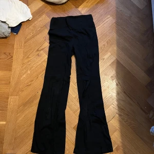 lågmidjade svarta flare leggings  - Svarta byxor med bootcut-modell och låg midja. De har en enkel och stilren look, perfekta att matcha med en crop top eller hoodie. Materialet känns mjukt och stretchigt, vilket gör dem riktigt sköna att ha på sig hela dagen.