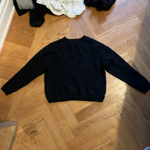 Svart stickad tröja med lång ärm - En enkel svart stickad tröja med rund hals och långa ärmar. Perfekt för lager-på-lager och funkar till det mesta. Klassisk och stilren modell som är lätt att matcha med andra plagg.