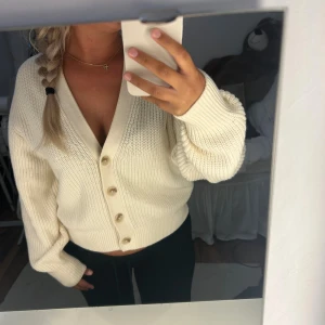 Krämvit kofta från H&M med knappar - Säljer en krämvit stickad kofta från H&M i storlek S. Koftan har v-ringning, ribbade muddar och fyra snygga knappar framtill. Modellen är lite loose och passar perfekt till jeans eller kjol. Supermysig och enkel att styla.