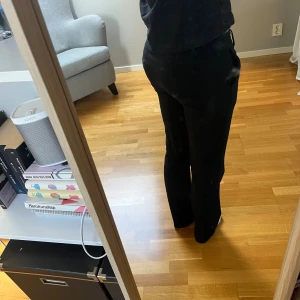 Low waist svarta kostymbyxor med raka/utsvängda ben - Low waist nygga svarta kostymbyxor med klassisk rak/utsvängd passform och mycket låg midja från Bikbok. Byxorna har diskreta fickor i sidorna och hällor för bälte. Perfekt till nästan alla looks.