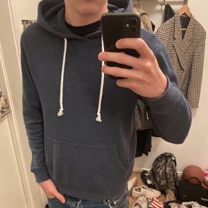 Mörkblå hoodie från Pier One - Mörkblå hoodie från Pier One med vita snören och klassisk känguruficka framtill. Tröjan har huva och långa ärmar, perfekt för chill dagar. Mjuk och skön bomullsblandning som passar till jeans eller joggers.