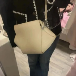 Beige axelväska i skinn - Säljer en stilren beige axelväska i skinn med minimalistisk design och justerbar axelrem. Perfekt storlek för att få plats med allt du behöver och passar till många olika outfits. Enkel att matcha och superpraktisk för vardagen.