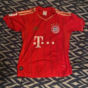 Bayern München Müller #25 Adidas tröja XS - Röd Bayern München fotbollströja från Adidas med guldiga detaljer, svarta ränder och klubbmärke broderat på bröstet. Nummer 25 och Müller på ryggen. Tillverkad i lätt och ventilerande material, perfekt för match eller träning.