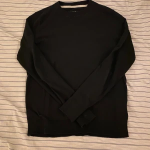 Svart stickad tröja  - En stilren svart stickad tröja med rund hals och ribbade muddar. Perfekt för dig som gillar enkel och clean look. Långärmad modell som passar till jeans eller chinos. Materialet är mjukt och skönt mot huden.