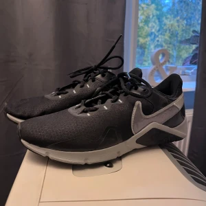 Nike Skor - Snygga svarta Nike sneakers med grå detaljer och mönstrad textil på ovansidan. Skorna är i utmärkt skick 9,9/10, storlek 42 (pris kan diskuteras) köpte för ett tag sen men bara använt någon gång inomhus så vet inte ny pris 