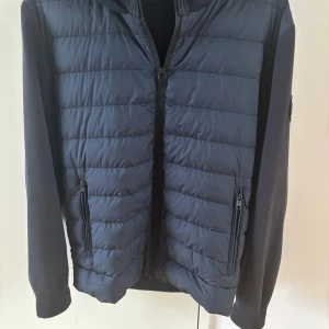 Svart Cardigan från Woolrich, M - Svart Cardigan från Woolrich i storlek M. Den har quiltad design, dragkedja framtill och två sidofickor med dragkedja. Använd fåtal gånger då den är för stor för mig. Köpt på Farfetxh för 6. Priset ej hugget i sten