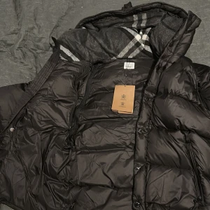 Burberry Jacka med avtagbara Armar - En perfekt Burberry-jacka, speciellt nu till hösten och vintern. Det som gör den ännu mer värd är att du kan ta bort ärmarna och använda den som väst – perfekt för olika väder och outfits. Klassisk Burberry-stil med rutigt foder och exklusiv känsla. Storlek M, men passar även S. 🖤 Notera: Produkten postas endast – ingen mötesaffär. 📌 Läs gärna bio på min Plick-profil innan köp.