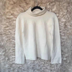 Vit polotröja i ull och kashmir från Benetton - Vit polotröja från United Colors of Benetton, tillverkad i Italien. Mjuk och lyxig känsla tack vare mixen av 70% ull, 20% polyamid och 10% kashmir. Väl använd. B 41 cm, L 51 cm.