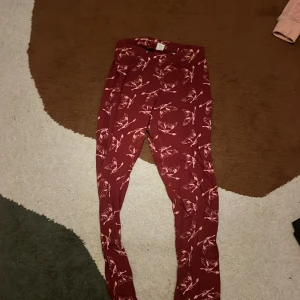 Harry Potter x H&M vinröda leggings - Snygga vinröda leggings från Harry Potter x H&M med ljusrosa ugglemönster. Byxorna har elastisk midja och är gjorda i mjukt material som passar perfekt för chill dagar. Perfekt för dig som älskar magi och vill ha något bekvämt och unikt.