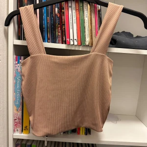 Linnetopp med breda axelband och ribbad struktur strl: XS - Säljer en beige linnetopp med breda axelband och ribbad struktur. Toppen har en fyrkantig halsringning och är croppad i modellen, perfekt för att styla med höga jeans eller kjol. Materialet är mjukt och stretchigt för en bekväm passform.