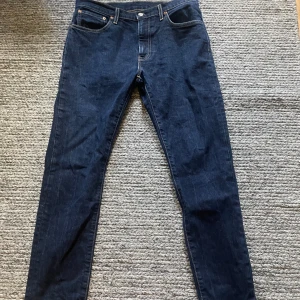 Levi's 512 mörkblå jeans slim fit - Mörkblå Levi's 512 jeans med slim fit och klassisk femficksdesign. Jeansen har raka ben, snygga kontrastsömmar och är tillverkade i slitstarkt denim. Perfekta för dig som gillar en smalare siluett och tidlös stil.