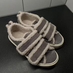 Grå mocka sneakers från Inuikii - Säljer nu mina gråa sneakers från Inuikii med fluffig vit fuskpäls runt hela skon och breda kardborreband. Skorna har en platt vit sula och är tillverkade i mocka med pälsfoder för extra mysig känsla. Perfekta för dig som gillar unik design och komfort. Är i storlek 39, använda 1 gång. Helt slutsålda överallt, Nypris 2599kr🤎