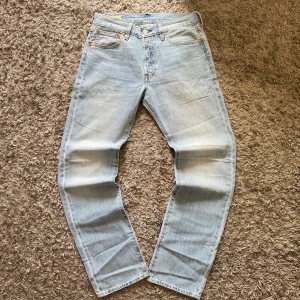 Levi's 501 ljusblå jeans W29 L32 - Ljusblå Levi's Premium 501 jeans med klassisk femficksdesign och raka ben. Jeansen har silverfärgad knapp, bruna sömmar och den ikoniska röda Levi's-taggen på bakfickan. Tillverkade i slitstarkt bomullsjeansmaterial och har en normal passform. Villig att gå ner i pris. Skicka bud!
