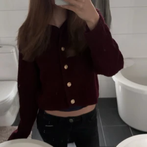 Vinröd stickad kofta med guldknappar - Mysig vinröd stickad kofta med snygga guldknappar framtill. Modellen har långa ärmar. Perfekt för lager-på-lager och ger en trendig vibe till din outfit. Hör av er vid några frågor! Accepterar dem flesta buden!