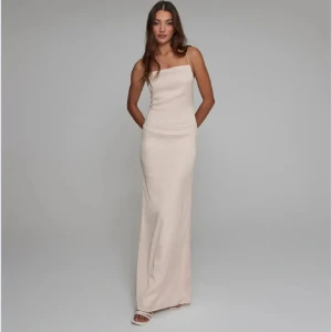 Champagnefärgad långklänning med smala axelband - Supersnygg långklänning i champagnefärg med smala axelband och rak siluett. Klänningen har öppen rygg och minimalistisk design, perfekt för dig som gillar stilrena och eleganta plagg. Materialet ser ut att vara mjukt och följsamt.