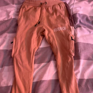 Beige byxor från Hoodrich S - Säljer ett par snygga beiga mjukisbyxor från Hoodrich i storlek S. Byxorna har dragsko i midjan, sidofickor med dragkedja och tryckt logga på benet.