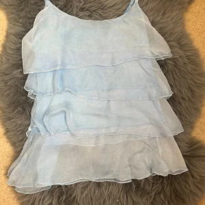 Ljusblå volangig linnetopp i silke - Made in Italy silk ruffle top. Unfortunately, I tried to iron it and burned it slightly on the side, but it’s not very visible