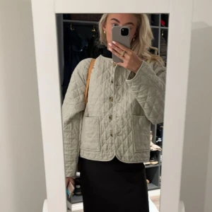 Beige quiltad jacka med knappar - Säljer en beige quiltad jacka med stora fickor framtill och knäppning med knappar. Jackan har en boxig, loose passform och är perfekt för lager-på-lager. Snygg och trendig modell som passar till många outfits.
