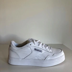 Vita Reebok sneakers  - Klassiska vita Reebok sneakers med låg profil och stilren design. Skorna har snörning, rund tå och är tillverkade i vitt skinn med diskreta detaljer och Reebok-logga på sidan och hälen. 